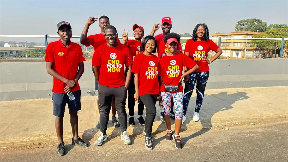 Rotary volunteers carrying blue vaccine carriers in Zambia — door-to-door mobilization